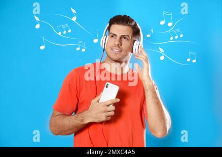 Uomo con telefono cellulare che ascolta musica tramite cuffie su sfondo blu Foto Stock