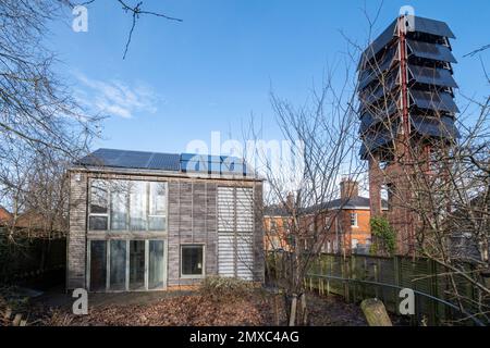 Pannelli solari su una torre di perforazione presso la vecchia stazione dei vigili del fuoco dell'esercito a Bordon, Hampshire, Inghilterra, Regno Unito, ora eco-stazione, accanto a un eco-house mostra Foto Stock