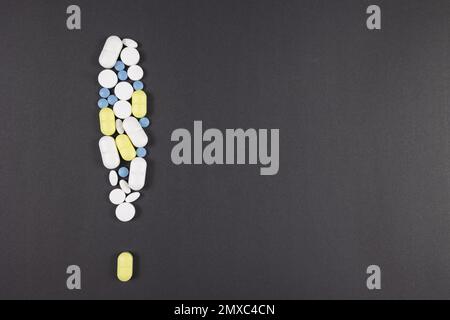 Segnale di avvertimento realizzato con pillole e farmaci isolati su sfondo nero o grigio. Effetti collaterali di farmaci o droghe tossiche concetto foto. Foto Stock