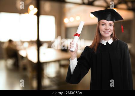 Allievo felice con cappello di laurea e diploma in ufficio, spazio per il testo Foto Stock