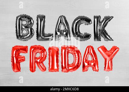 Frase NERO VENERDÌ fatto di foglio palloncino lettere su sfondo bianco di legno Foto Stock