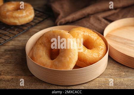 Deliziose ciambelle in scatola su tavolo di legno Foto Stock