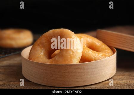 Deliziose ciambelle in scatola su tavolo di legno, primo piano Foto Stock