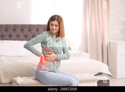 Donna che soffre di mal di schiena dopo aver dormito su un materasso a disagio a casa Foto Stock