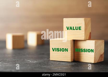 Cubi di legno con parole VALORE, VISIONE e MISSIONE su tavola di pietra grigia, closeup Foto Stock