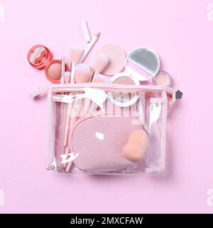 Borsa cosmetica in plastica con prodotti per il trucco e accessori di bellezza su sfondo rosa, piatto Foto Stock