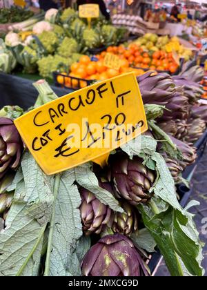 Mercato, prezzo italiano sui carciofi freschi con focalizzazione selettiva in un mercato agricolo aperto in Italia. carciofi freschi e maturi su supporti di verdure o. Foto Stock