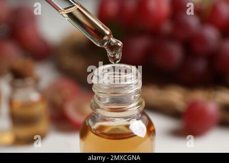 Gocciolamento di olio di semi di uva naturale in bottiglia, primo piano. Cosmetico organico Foto Stock