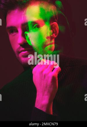 Doppia esposizione, colore e ritratto di un uomo che pensa isolato su uno sfondo scuro in studio. Texture, design e volto di un uomo con overlay colorato Foto Stock