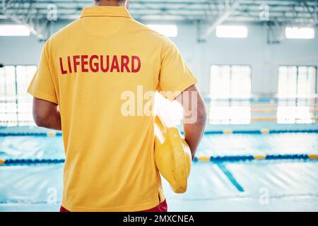 Sicurezza, sicurezza o bagnino presso una piscina per aiutare il pubblico a salvare il pericolo o annegare in acqua. Vista posteriore, fiducia o uomo in piedi con a. Foto Stock