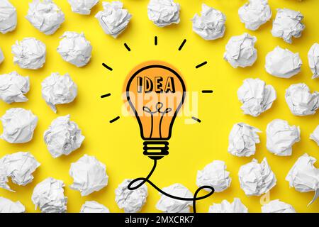 Concetto di idea. Composizione con palline di carta stropicciate e disegno di lampadina su fondo giallo, piatto Foto Stock