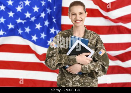 Soldato femminile con tavoletta e bandiera americana sullo sfondo. Servizio militare Foto Stock