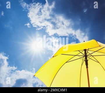 Ombrello giallo moderno contro il cielo blu. Protezione solare Foto Stock