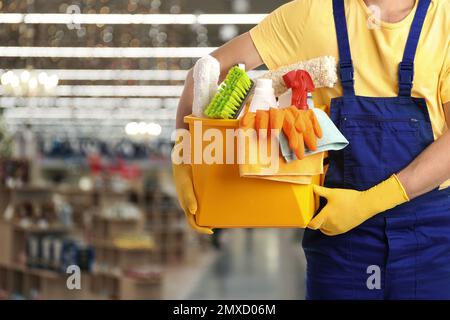 Janitor maschio con i rifornimenti di pulizia in centro commerciale, primo piano. Spazio per il testo Foto Stock