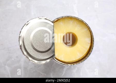 Teglia aperta con ananas in scatola su tavolo in marmo grigio chiaro, vista dall'alto Foto Stock