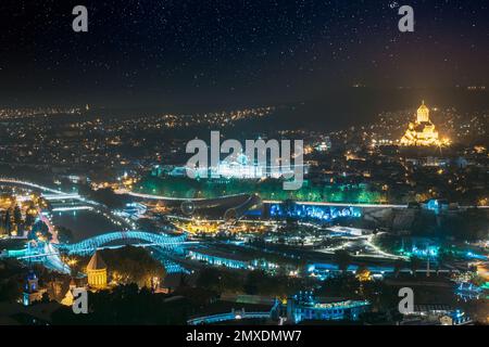 Tbilisi, Georgia. Incredibile cielo stellato luminoso sopra la Casa di Giustizia, Ponte della Pace, Sala Concerti di sera o illuminazione notturna. Panoramica notturna serale Foto Stock