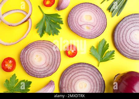 Composizione piatta con fette di cipolla e spezie su fondo giallo Foto Stock