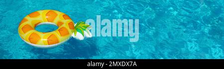 Luminoso anello di ananas gonfiabile che galleggia in piscina il giorno di sole, spazio per il testo. Design del banner Foto Stock