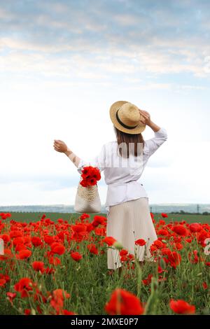 Donna con borsetta e fiori di papavero in campo bello Foto Stock