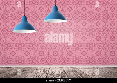 Eleganti lampade a sospensione appese vicino alla parete rosa della stanza Foto Stock