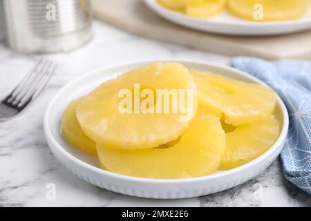 Gustose fette di ananas in scatola su un tavolo di marmo bianco, primo piano Foto Stock