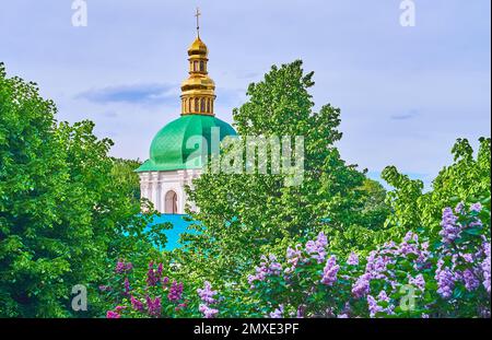 I lussureggianti alberi verdi e i lilacchi fioriti nel giardino del Monastero della Grotta di Lavra di Kyiv Pechersk con vista sulla cupola dell'esaltazione del Coira di Santa Croce Foto Stock