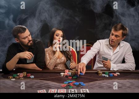Gruppo di giovani amici ricchi stanno giocando a poker nel casinò. Foto Stock