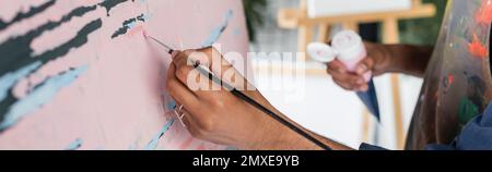 Vista ritagliata dell'artista afro-americano dipinto su tela in workshop, banner, immagine stock Foto Stock