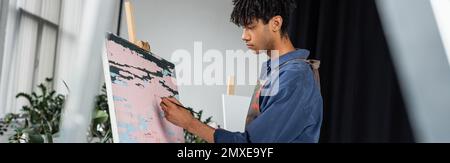 Vista laterale della pittura di artista afro-americano su tela in studio, banner, immagine di scorta Foto Stock