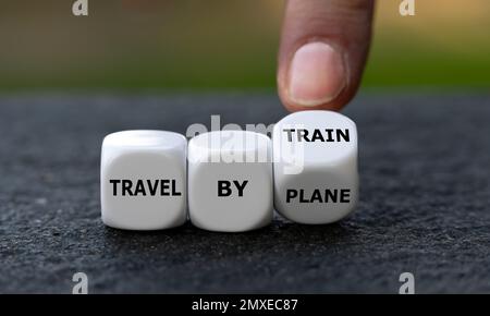 La mano gira i dadi e cambia l'espressione "viaggio in aereo" in "viaggio in treno". Simbolo per la riduzione delle emissioni viaggiando in treno invece che in tra Foto Stock