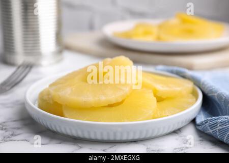 Gustose fette di ananas in scatola su un tavolo di marmo bianco, primo piano Foto Stock