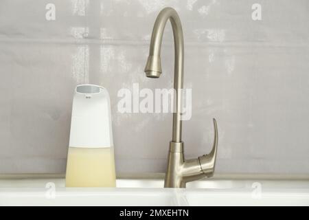 Dispenser di sapone automatico moderno vicino al lavandino in bagno,  guardaroba Foto stock - Alamy