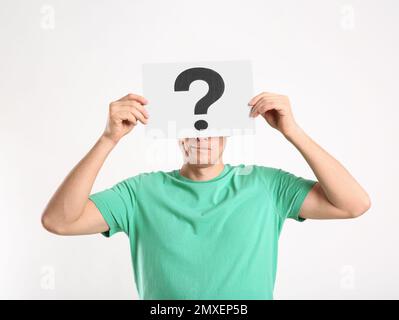 Uomo che tiene carta con punto interrogativo su sfondo bianco Foto Stock