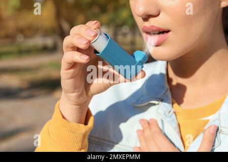 Donna che usa inalatore di asma all'aperto, primo piano. Assistenza sanitaria Foto Stock