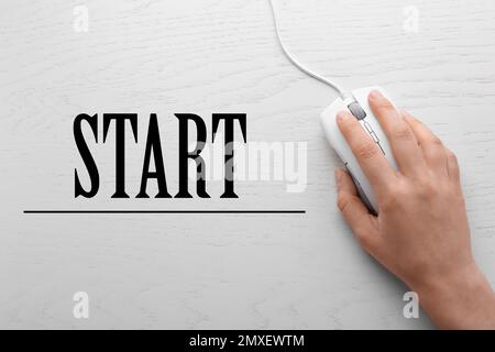 Donna con computer mouse e parola INIZIARE su sfondo di legno, vista dall'alto Foto Stock