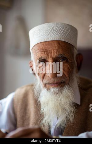 Vecchio venditore di scialli di lana con barba bianca e cappello bianco, Islampur, Swat Valley, Pakistan Foto Stock