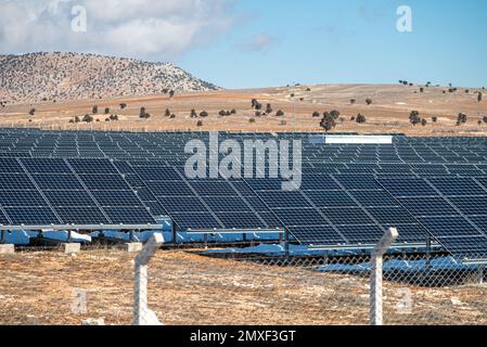 Campo solare con pannelli solari recintati al tramonto Foto Stock