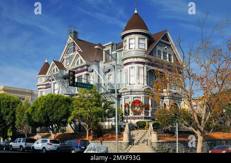 Splendida casa vittoriana a San Francisco, caratterizzata da dettagli intricati, finestre bovindo e una torretta, adagiata su un vibrante sfondo urbano. Foto Stock