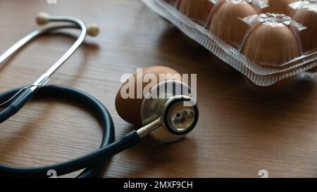 Uova e stetoscopio su tavola di legno. Concetto di salute, dieta e nutrizione. Foto Stock