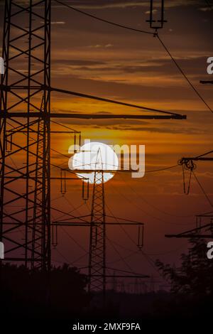 Poli di alimentazione davanti al tramonto in controluce Foto Stock