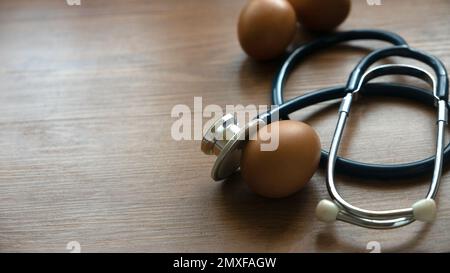 Uova e stetoscopio su tavola di legno. Concetto di salute, dieta e nutrizione. Foto Stock