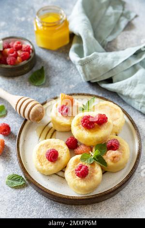 Frittelle di ricotta, tavolo per la colazione del mattino. Casetta casereccia frittelle senza glutine (sciroppi, frittelle cagliate) con bacche su fondo di pietra. Foto Stock