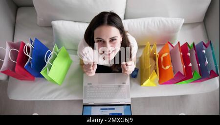 Giovane donna seduta sul divano lo Shopping Online con le borse della spesa. Foto Stock