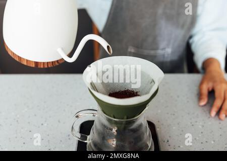 Primo piano di un barista irriconoscibile che prepara il caffè con un filtro. Processo di un metodo a gravità per la preparazione del caffè. Foto Stock