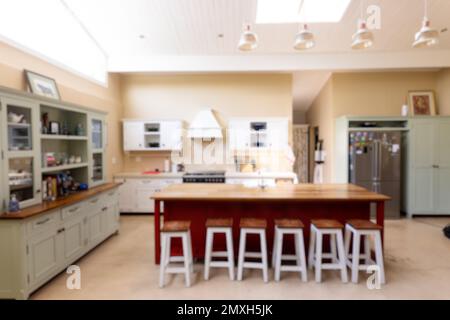 Lampade pendenti appese sul soffitto sopra l'isola di cucina in legno e sgabelli in cucina moderna Foto Stock