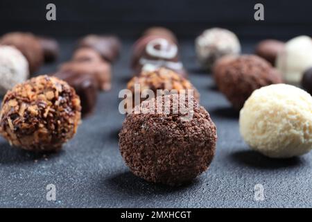 Diverse gustose caramelle al cioccolato su tavola nera, primo piano Foto Stock