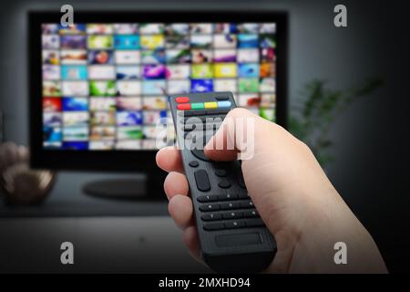 Servizi video in streaming. Donna che usa il telecomando per cambiare canale sulla TV, primo piano Foto Stock