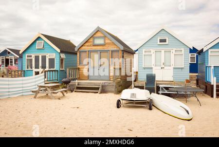 Fila di case in legno sulla spiaggia di sabbia. Hengistbury Head, Dorset, Regno Unito Foto Stock