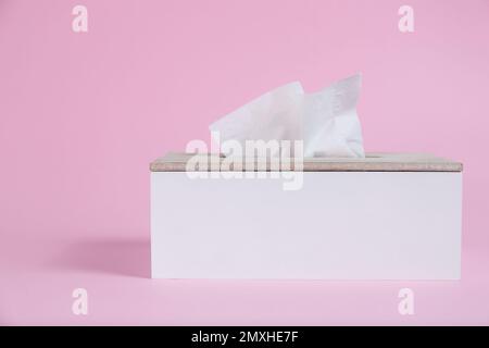 Supporto con fazzolettini di carta su sfondo rosa Foto Stock