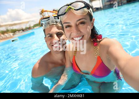 Felice coppia che prende selfie in piscina. Vacanze estive Foto Stock